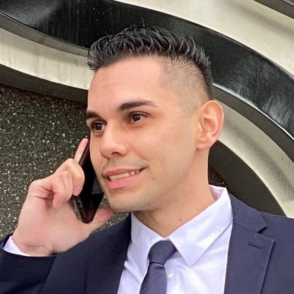 Headshot of Christopher Gil talking on a cell phone.